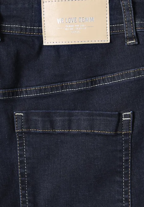 Rückansicht einer dunklen Jeans mit Gesäßtasche und Lederetikett 'WE LOVE DENIM'.