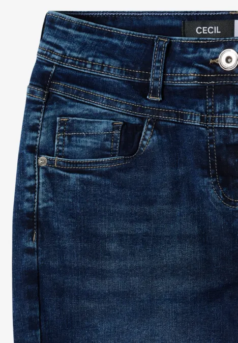Close-up van een donkerblauwe denim jeans met voorzakken, ceintuurlussen, knoopsluiting en CECIL-label.