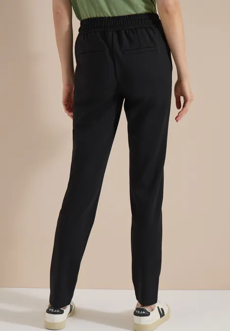 Spodnie Mid Waist z wąskimi nogawkami o Casual Fit Black Kobieta widziana od tyłu w czarnych, dopasowanych, casualowych spodniach.
