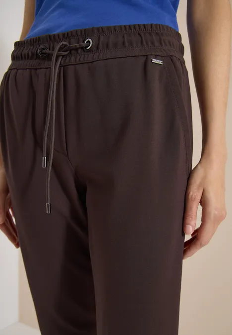 Mid Waist Slim Leg Hose in casual pasvorm truffle brown Donkerbruine joggingbroek met elastische band, trekkoord en zijzakken, gecombineerd met een blauw bovenstuk.