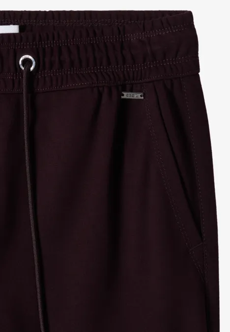 Nahaufnahme einer dunkelroten Jogginghose mit elastischem Bund, Tunnelzug und seitlicher Tasche.