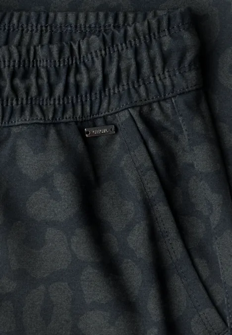 Gros plan sur un pantalon noir à motif discret, taille élastique et poche latérale.
