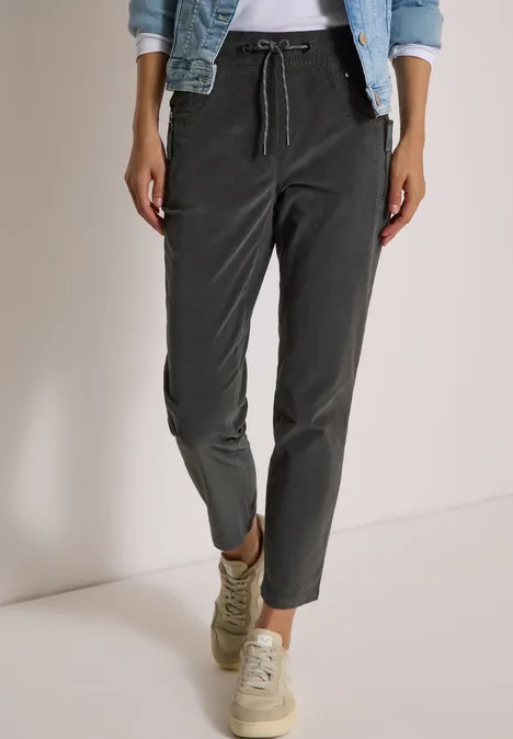 Mid Waist Slim Leg Hose im Casual Fit easy khaki Dunkelgraue, lässige Hose mit Tunnelzug, kombiniert mit hellen Sneakers und Jeansjacke.