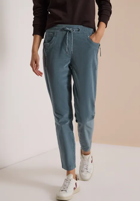Mid Waist Slim Leg Hose im Casual Fit dove blue Damen-Jogginghose in Hellblau mit Gummizug und Taschen, kombiniert mit weißen Sneakern.