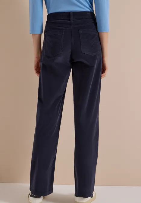 High Waist Wide Leg Hose im Loose Fit dark blue corduroy Rückansicht einer Person in dunkelblauen Cordhose und hellblauem Oberteil.