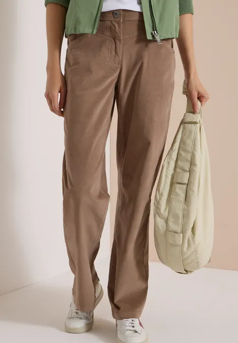 High Waist Wide Leg Hose im Loose Fit earthy taupe Person trägt braune Cordhose, weiße Sneaker und hält eine beigefarbene gesteppte Tasche.
