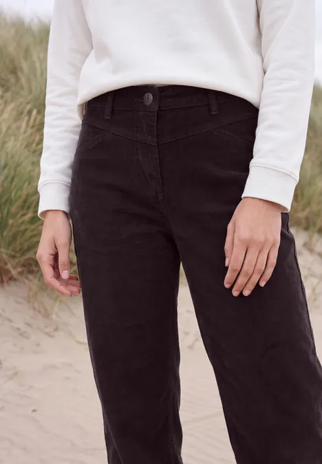 Broek met High Waist en Wide Leg pijpen in een Loose Fit pasvorm berry red Een persoon staat op zand, draagt witte trui en zwarte broek, met duinen op de achtergrond.