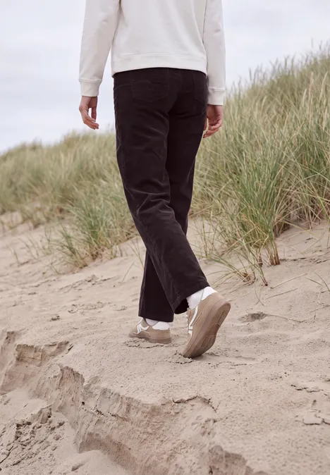 Broek met High Waist en Wide Leg pijpen in een Loose Fit pasvorm berry red Een persoon in een zwarte broek en witte sneakers loopt over zandduinen op het strand.