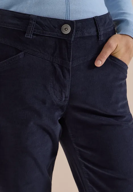 Dunkelblaue Cordhose mit Knopf, sichtbaren Nähten und Hand in Tasche.