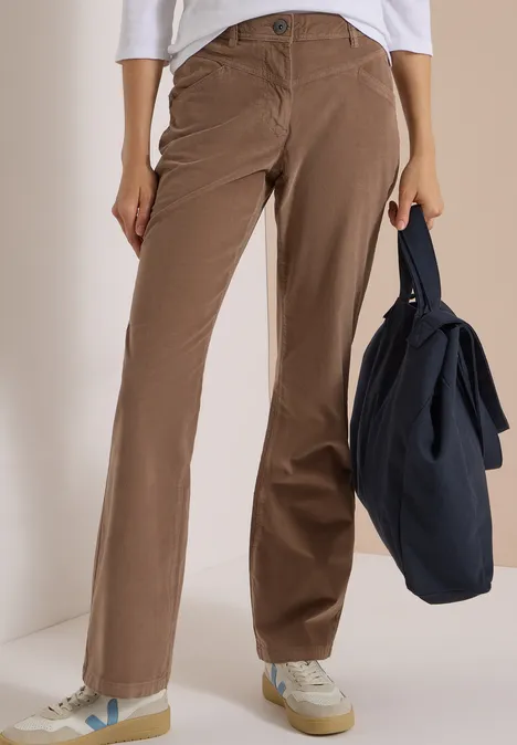 High Waist Bootcut Hose im Slim Fit earthy taupe Eine Person trägt braune Cordhose und weiße Sneakers, hält eine dunkelblaue Tasche in der Hand.