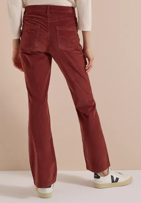 High Waist Bootcut Hose im Slim Fit dark russet red Rote Cordhose mit weitem Bein, Gesäßtaschen, kombiniert mit weißen Sneakern auf neutralem Hintergrund.
