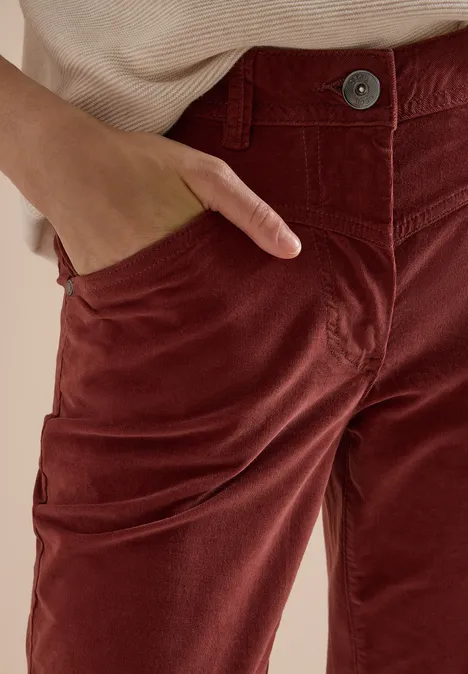 High Waist Bootcut Hose im Slim Fit dark russet red Nahaufnahme einer Person mit braunroten Cord-Hosen und Hand in der Tasche.