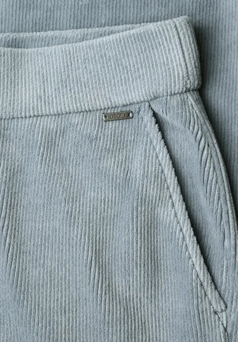 Nahaufnahme einer hellgrauen Cordhose mit Bündchen und seitlicher Reißverschlusstasche.