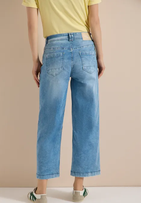 Vue de dos d’une personne en jean large bleu clair mi-long et t-shirt jaune.