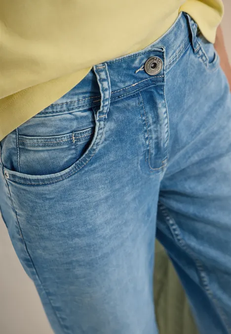 Jean bleu taille haute avec poches avant, associé à un haut jaune.