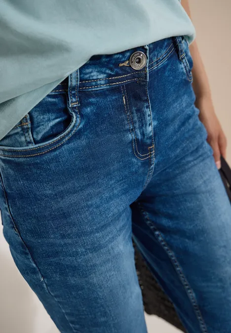 Gros plan d'un torse en jean bleu et haut vert décontracté.