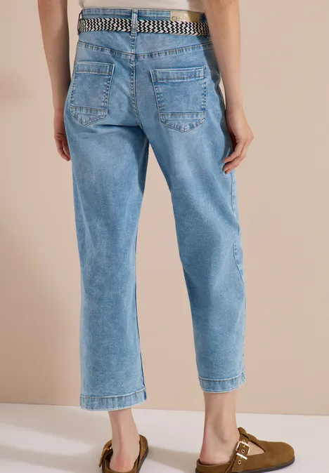 Jean 7/8 à jambes larges avec ceinture fresh blue random wash Vue arrière d’une personne en jean bleu clair court, ceinture à clous et mules marron.