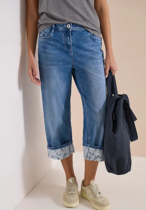 7/8 Wide Legs jeans met omgeslagen detail mid blue wash Opgerolde spijkerbroek, casual T-shirt, sneakers en een tas in de hand.
