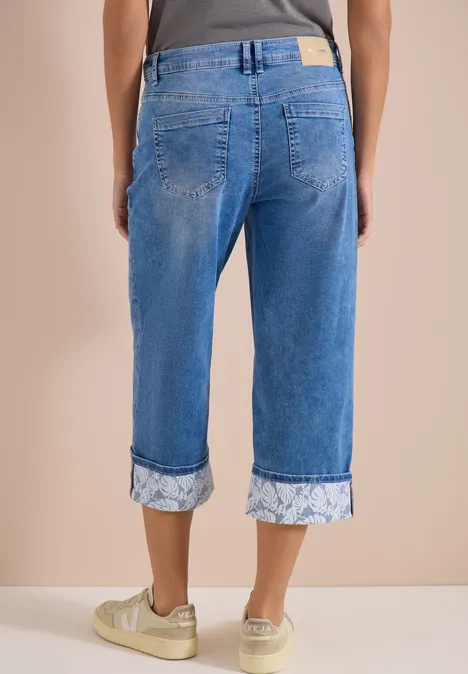 7/8 Wide Legs jeans met omgeslagen detail mid blue wash Achteraanzicht: lichtblauwe, opgerolde Capri-jeans met bloemenpatroon en witte sneakers met gouden accenten.