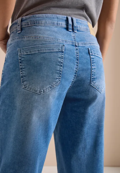7/8 Wide Legs jeans met omgeslagen detail mid blue wash Persoon van achteren in losse blauwe jeans met hoge taille, zichtbare achterzakken en riemlussen.