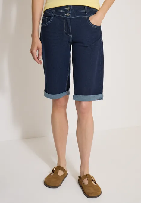 Shorts met High Waist en Wide Leg pijpen in een Loose Fit pasvorm rinsed wash Persoon in donkere, knielange jeansshorts met omslag en bruine instappers.