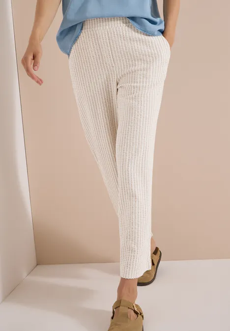 Wide Leg Hose in Seersucker-Qualität grain beige Beine in hellen, gerippten, knöchellangen Hosen und klassischen Loafers vor neutralem Hintergrund