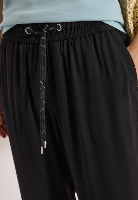 Zwarte stofbroek met elastische taille en trekkoord, losse pasvorm.