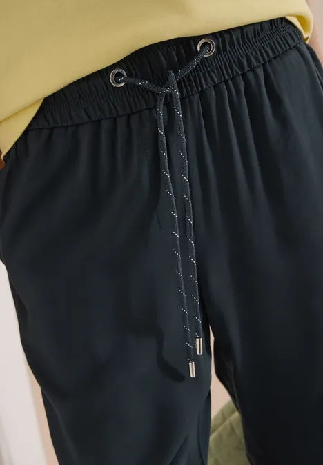 Pantalon noir décontracté avec taille élastique, cordon ajustable, coutures discrètes et embouts argentés.