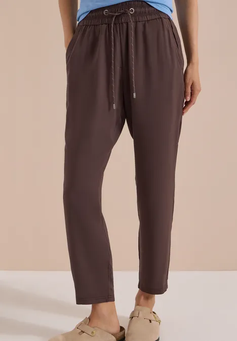 Damesbroek in bruin lichtgewicht stof, met elastische taille, koord en taps toelopende pijpen.