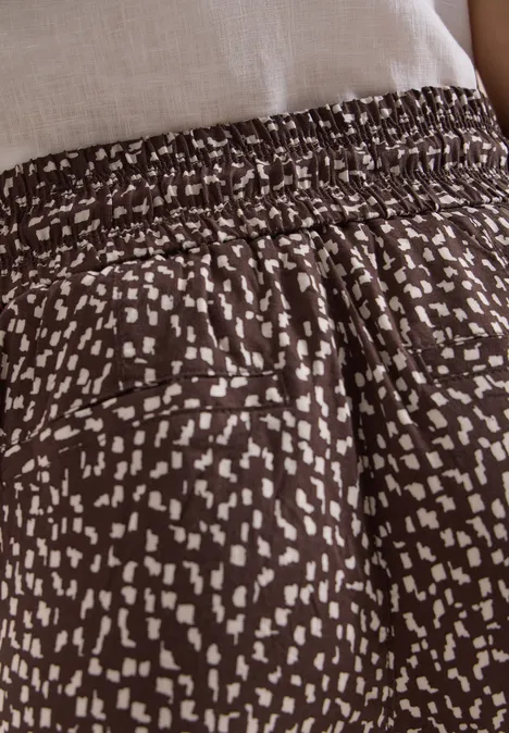 Braune, locker sitzende Hose mit elastischem Bund und unregelmäßigem weißen Punktemuster.