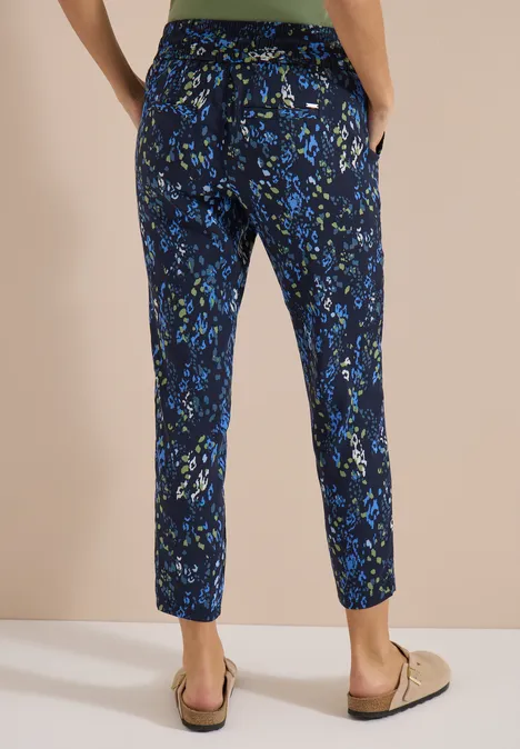 Pantalon en tissu bleu foncé à motifs floraux verts et bleus, longueur cheville, poches latérales.