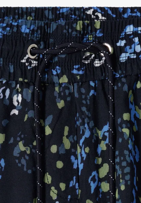 Imprimé abstrait bleu et vert sur ceinture élastique noire, cordon de serrage et œillets métalliques.