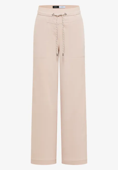 Beige, wijdvallende broek met koordsluiting en opgestikte zakken.