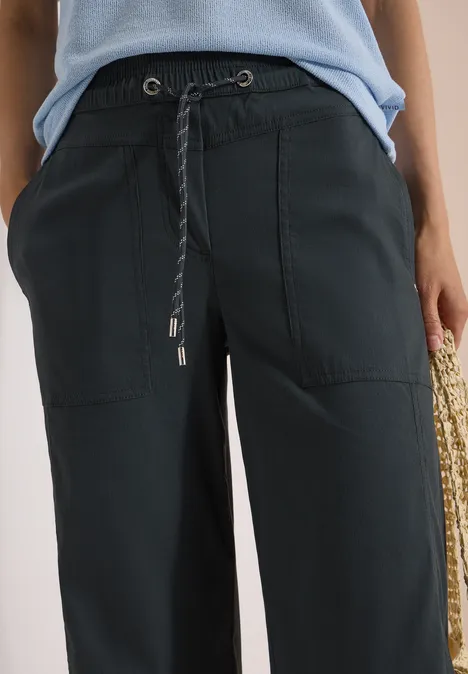 Zwarte, wijde broek met trekkoord en opgestikte zakken, gecombineerd met een lichtblauwe top.