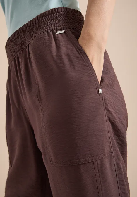 Nahaufnahme von lockeren, braunen Stoffhosen mit elastischem Bund und Taschen.