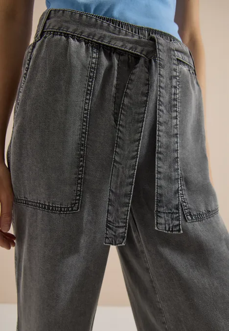 Schwarze, weite Jeans mit hohem Bund, Gürtel und großen aufgesetzten Taschen.