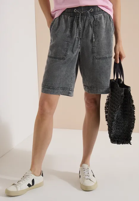 Shorts met Wide Leg pijpen en een Loose Fit pasvorm mid grey random wash Persoon draagt vergrijsde jeansshort met trekkoord, witte sneakers en zwarte gevlochten tas.