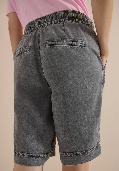 Shorts met Wide Leg pijpen en een Loose Fit pasvorm mid grey random wash Een persoon draagt grijze denim bermudashort met elastische tailleband, achter- en zijzakken, staat met handen in de zakken.