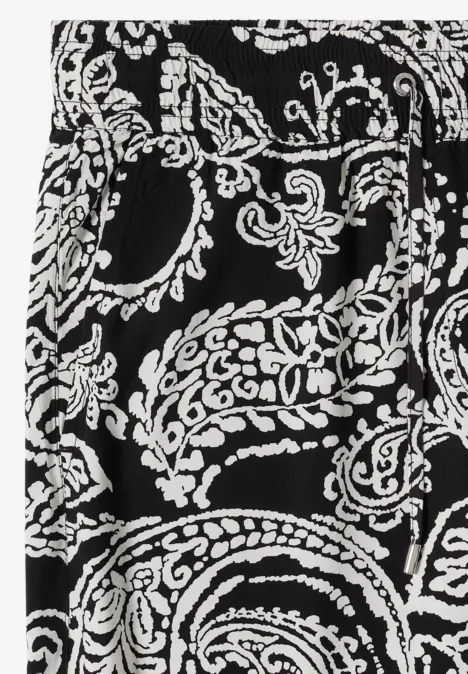 Nahaufnahme eines Stoffes mit schwarz-weißem Paisley- und Blumenmuster.