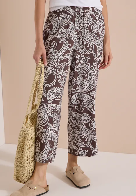 7/8 High Waist Wide Leg Hose im Loose Fit brown cacao Schwarz-weiße, locker geschnittene Palazzohose mit Paisley-Muster, dazu Basttasche und Loafers.