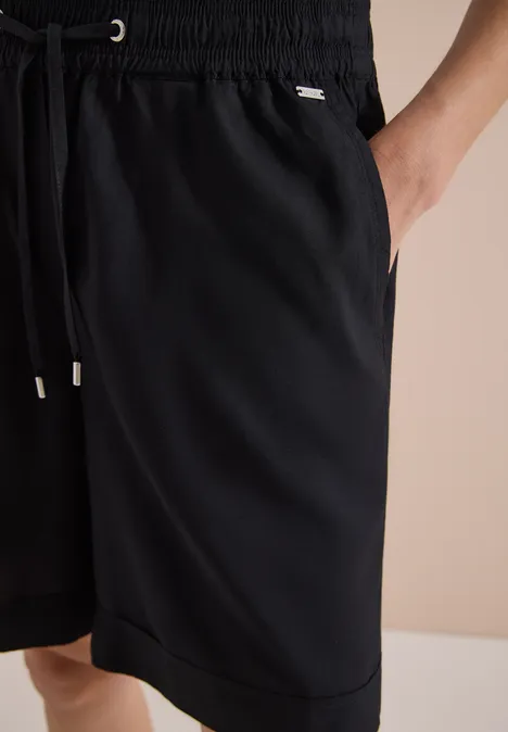 Schwarze, knielange Sporthose mit elastischem Bund, Kordelzug und seitlichen Eingrifftaschen.