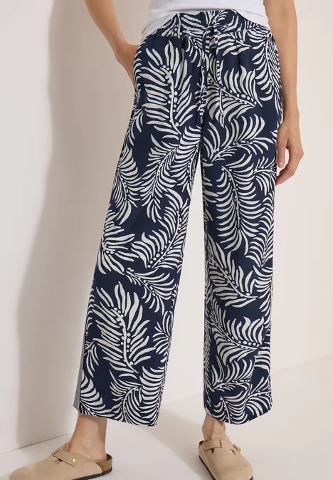 Pantalon fluide bleu marine à motif de feuilles blanches, coupe ample et estivale.
