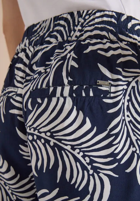 Pantalon bleu marine à motif de feuilles de palmier blanches, taille élastiquée et poche arrière.