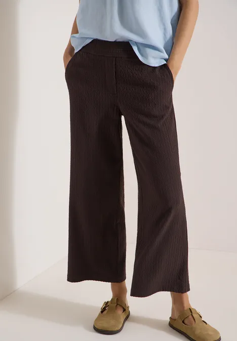 Loszittende damessbroek in bruin met fijne strepen, zijkantenzakken en enkellange wijdte voor een casual look.