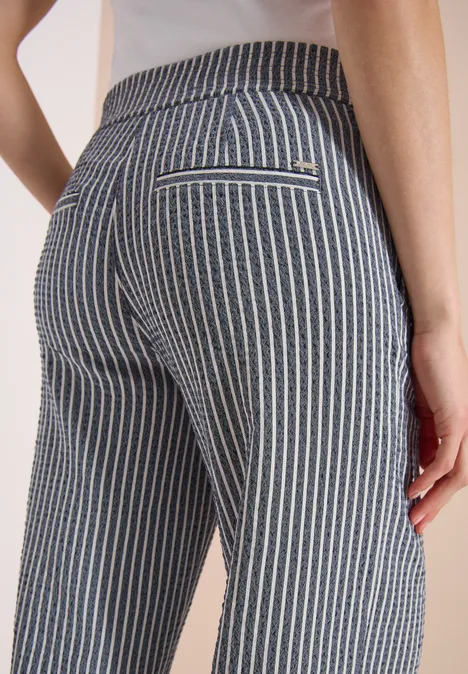 Rückenansicht einer Person in eng anliegenden, grau-weiß gestreiften Hosen.