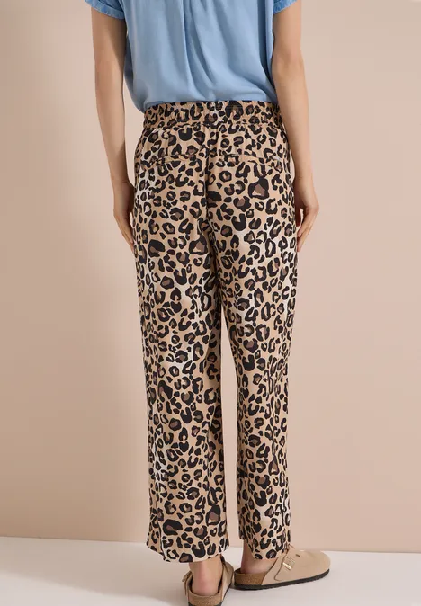 High Waist Wide Leg Hose mit Leo-Print urban taupe Rückansicht einer Person mit beige-schwarzer, weit geschnittener Leopardenhose, hellblauem T-Shirt und beigen Slippern.