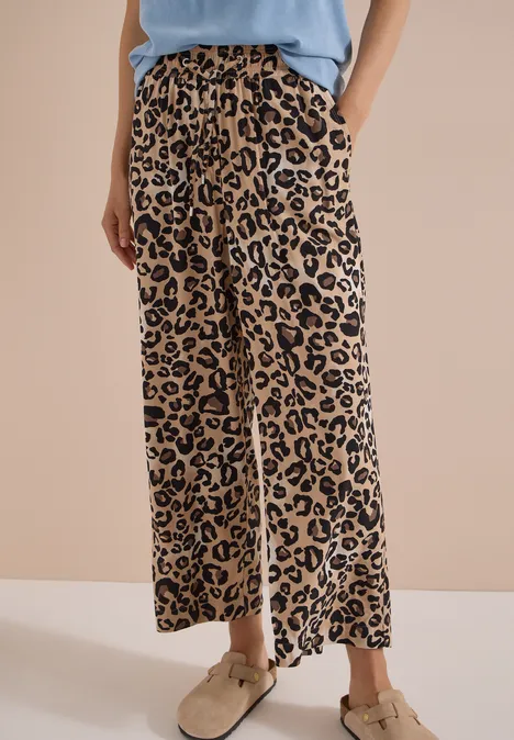 High Waist Wide Leg Hose mit Leo-Print urban taupe Beine in weiten, beige-schwarzen Leopardenhosen, kombiniert mit beigen Schuhen und lockerem Top.