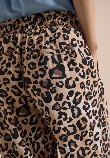 High Waist Wide Leg Hose mit Leo-Print urban taupe Frau trägt beigebraune Hose mit schwarzem Leopardenmuster, elastischem Bund und Gesäßtasche.