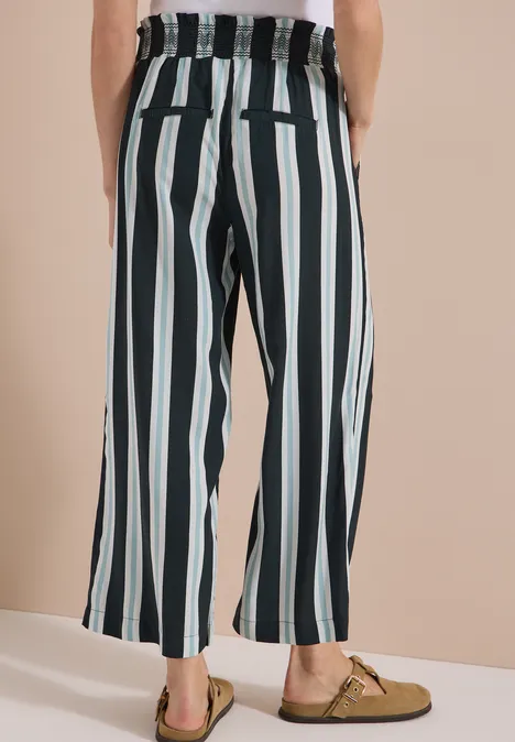 High Waist Wide Leg Hose mit Streifen palm breeze green Person von hinten in lockerer, hoch taillierter Hose mit schwarzen und weißen Längsstreifen und Mokassins.