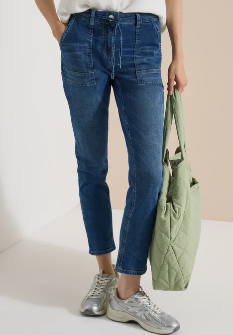 Straight Leg Jeans mit Gürteldetail mid blue used wash Hüfthohe, dunkelblaue Jeans mit Bündchen, grauen Sneakern und einer hellgrünen, gesteppte Tasche.